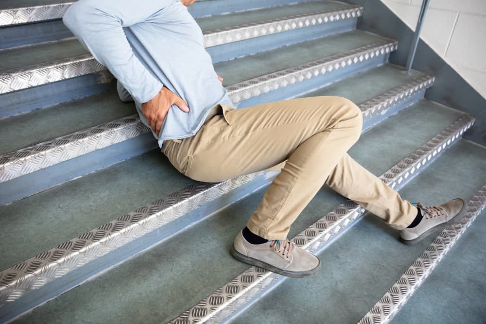 A Person Fallen Laying On Stairs Holding His Back